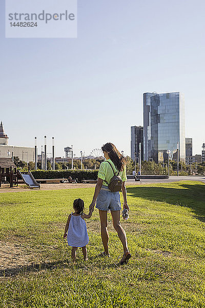 Mutter und Tochter gehen Hand in Hand in einem Park
