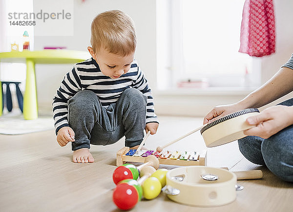 Mutter und Kleinkind spielen zu Hause mit Musikinstrumenten