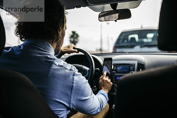 Geschäftsmann fährt Auto mit Handy als Navigationssystem