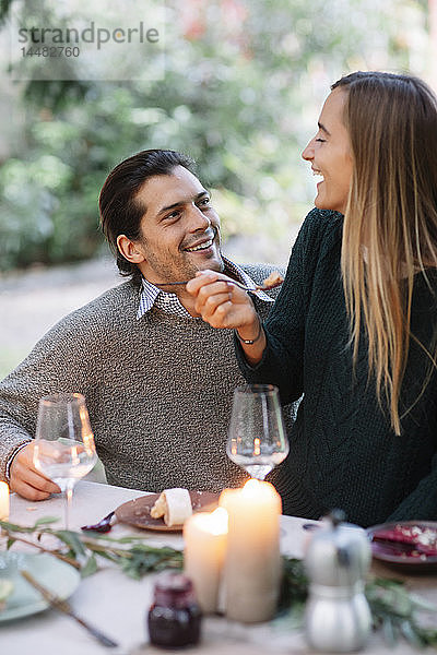 Glückliches Paar beim romantischen Essen bei Kerzenlicht am Gartentisch