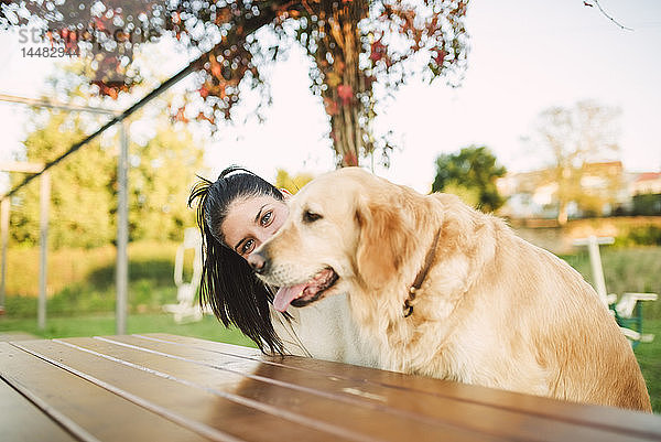 Porträt einer jungen Frau mit ihrem Golden-Retriever-Hund  die sich in einem Park ausruht
