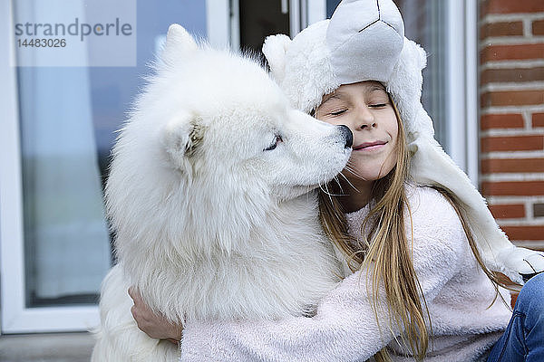 Mädchen umarmt ihren Hund auf der Terrasse