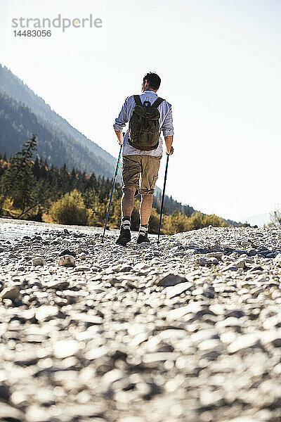 Österreich  Alpen  Mann auf einer Wanderung auf Kieselsteinen entlang eines Baches