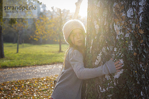 Junges Mädchen umarmt Baum im Herbst