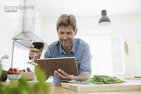 Reifer Mann in seiner Küche liest Rezept auf seinem digitalen Tablett