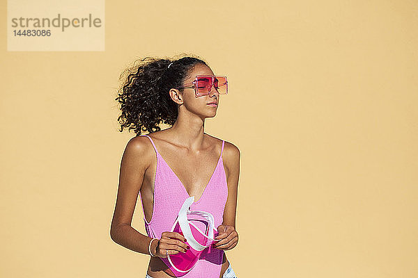Porträt einer Teenagerin mit Sonnenbrille  geschlossenen Augen  orangefarbener Wand