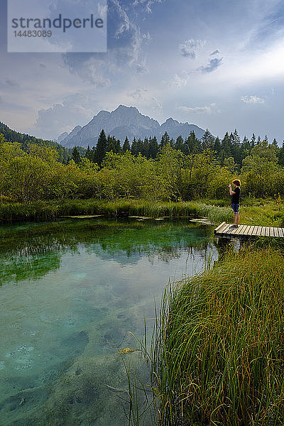 Slowenien  Gorenjska  bei Ratece  Sava Dolinka  Quelle  Zelenci-See  junger Mann am Steg stehend