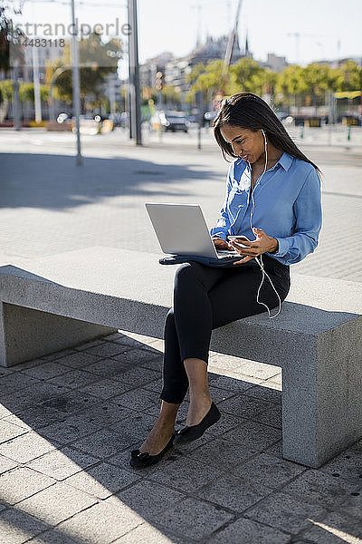 Geschäftsfrau mit Laptop und Smartphone in der Hand