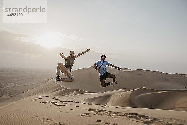 Namibia  Namib  zwei Freunde springen auf einer Wüstendüne in die Luft