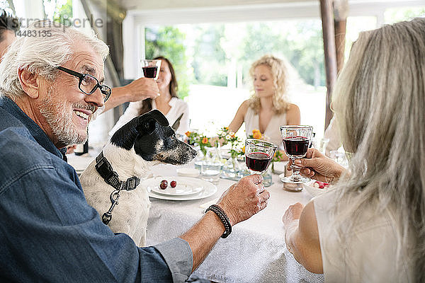 Älteres Ehepaar klimpert auf einer Familienfeier mit Weingläsern