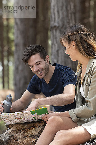 Junges Paar  das im Wald sitzend eine Karte liest