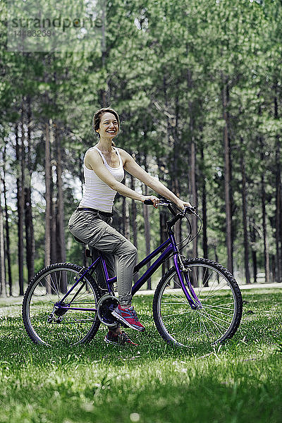 Frau auf Fahrrad im Wald sitzend