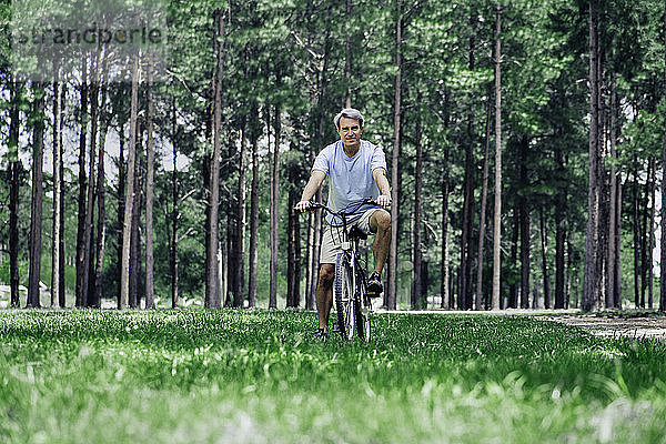 Älterer Mann sitzt auf einem Fahrrad im Wald