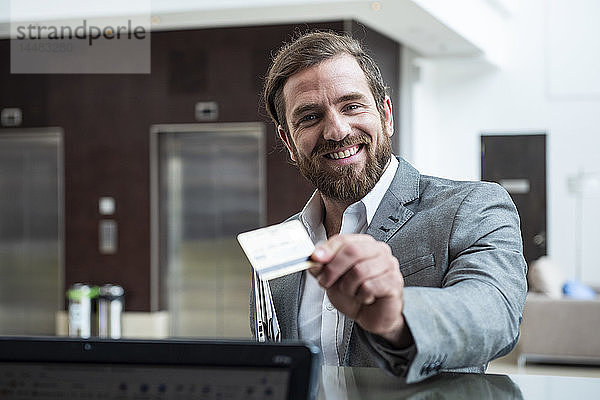 Geschäftsmann steht mit Kreditkarte an der Hotelrezeption
