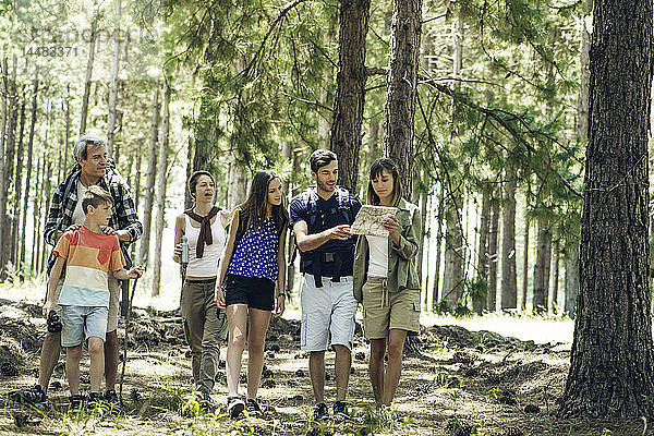 Familie  die im Wald stehend eine Karte liest