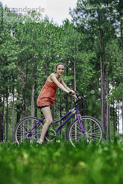 Teenager-Mädchen sitzt auf einem Fahrrad im Wald