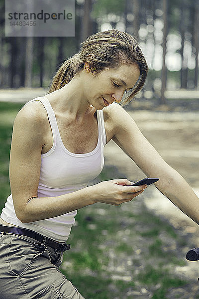 Ältere Frau benutzt Smartphone im Wald