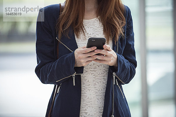 Frau benutzt Smartphone in der Hotellobby