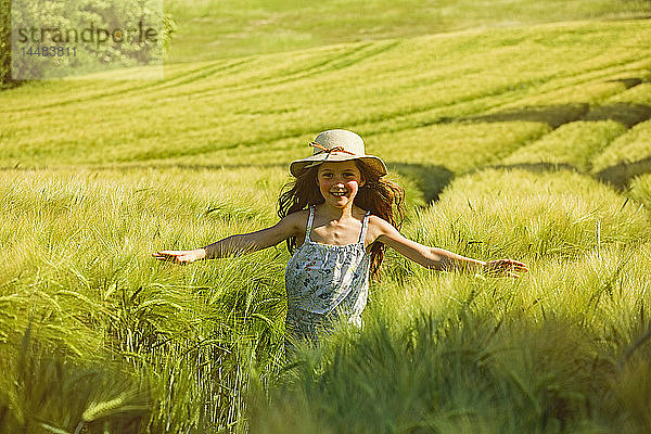 Porträt glückliches  sorgloses Mädchen  das auf einem sonnigen Feld läuft