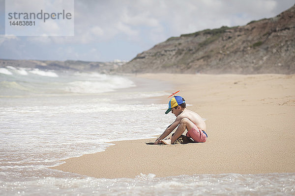 Junge spielt im Sand am sonnigen Meeresstrand  Lisboa  Lissabon  Portugal