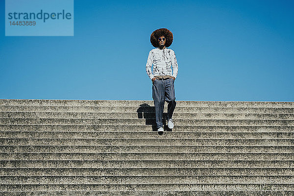 Porträt selbstbewusster  cooler junger Mann mit Afro auf sonnigen Stufen