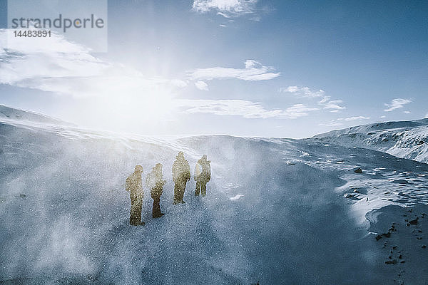 Spaziergänger in sonniger  windiger  schneebedeckter Landschaft  Reykjadalur  Island