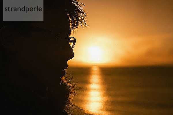 Silhouette Profil Teenager Junge Blick auf Sonnenuntergang über dem Meer