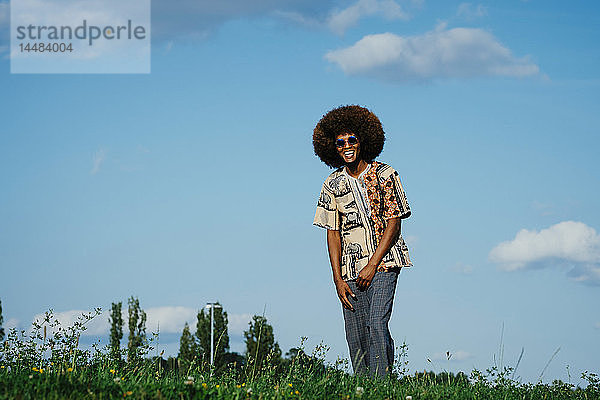 Porträt glücklicher junger Mann mit Afro im Park Gras