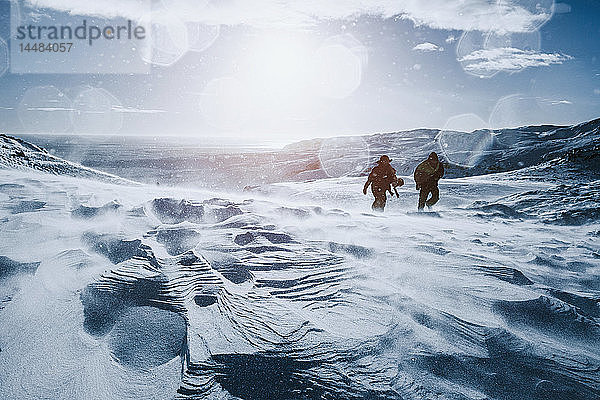 Vater und Sohn wandern an einem sonnigen  schneebedeckten Berg entlang  Reykjadalur  Island