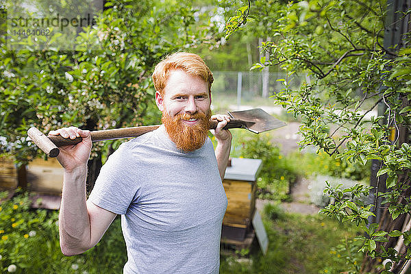 Porträt selbstbewusster  lächelnder Mann mit Schaufel im Garten