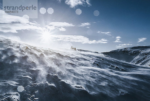 Spaziergänger auf einem sonnigen  windigen  schneebedeckten Berg  Reykjadalur  Island