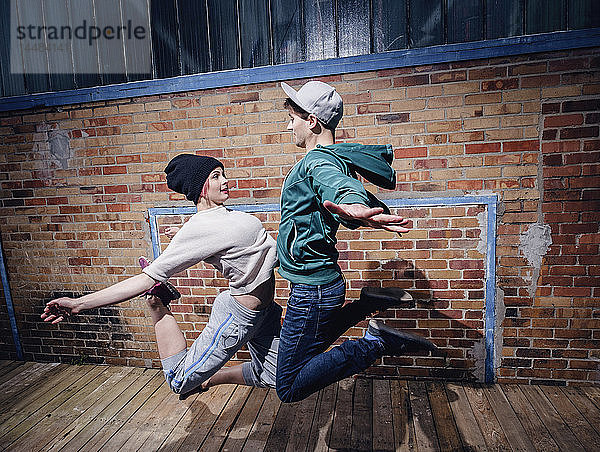 Moderne Tänzerinnen und Tänzer treten gegen eine Backsteinmauer an