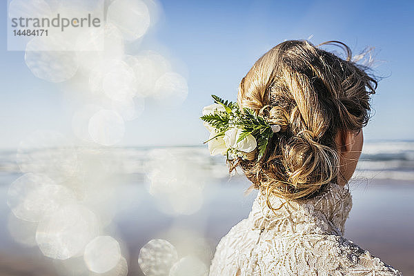 Blonde Braut mit Blumen im Haar am sonnigen Strand