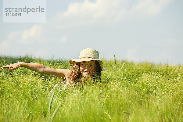 Unbekümmertes  glückliches Mädchen in einem sonnigen  grünen Weizenfeld