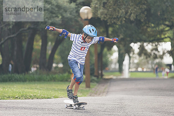 Junge spielt  fährt Skateboard im Park
