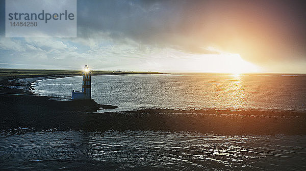 Idyllischer Sonnenuntergang über Meer und altem Leuchtturm  Reykjanesbaer  Island