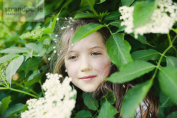 Porträt heiteres Mädchen in blühendem Busch stehend