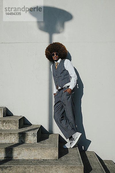 Porträt selbstbewusster  cooler  gut gekleideter junger Mann mit Afro auf städtischen Stufen