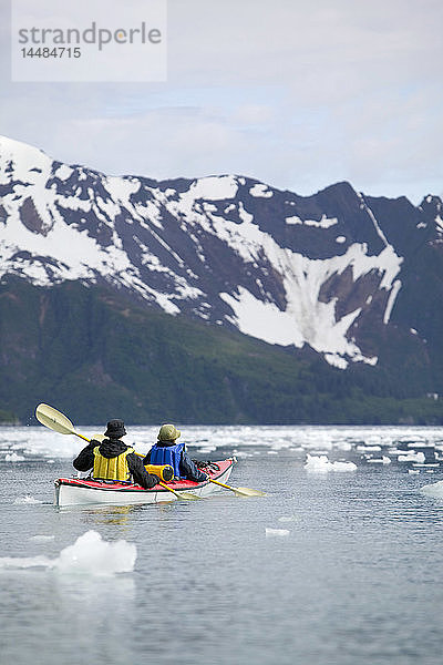 Zwei Kajakfahrer paddeln zwischen Eisbergen in der Aialik Bay im Kenai Fjords National Park im Sommer in Süd-Zentral-Alaska