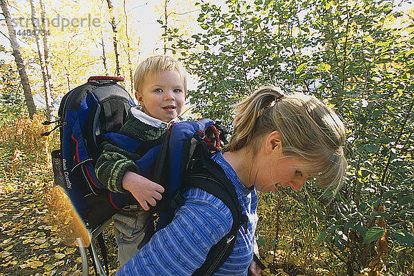 Mutter trägt Sohn im Rucksack auf Wanderung Chugach State Park Eagle River Valley Southcentral AK Herbst