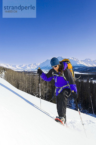 Eine Frau genießt einen sonnigen Tag beim Schneeschuhwandern in den Talkeetna Mountains in der Nähe des Matanuska-Gletschers. Winter in Süd-Zentral-Alaska.