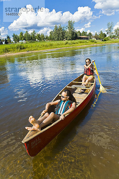Junge Frauen paddeln im Sommer in einem Tandemkanu auf dem Chena River in Fairbanks  Alaska  flussabwärts.