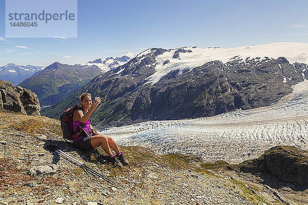 Wanderin macht eine Pause und telefoniert neben dem Exit Glacier im Harding Icefield bei Seward  Kenai Fjords National Park  Kenai Peninsula  Southcentral Alaska  Sommer  HDR