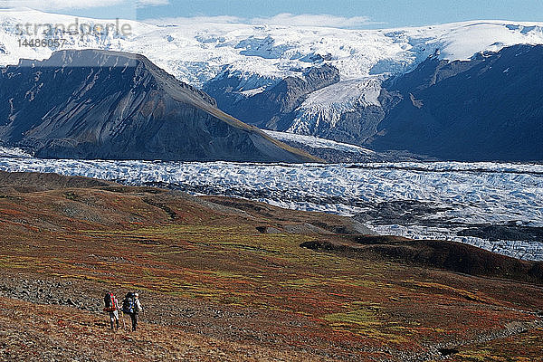 Zwei Rucksacktouristen wandern durch die Herbstlandschaft zum Long Glacier im Wrangell-St.Elias-Nationalpark in Süd-Zentral-Alaska.