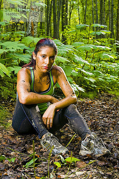 Junge hispanische Frau  die sich nach einem Lauf auf einem schlammigen Weg ausruht  Southcentral Alaska