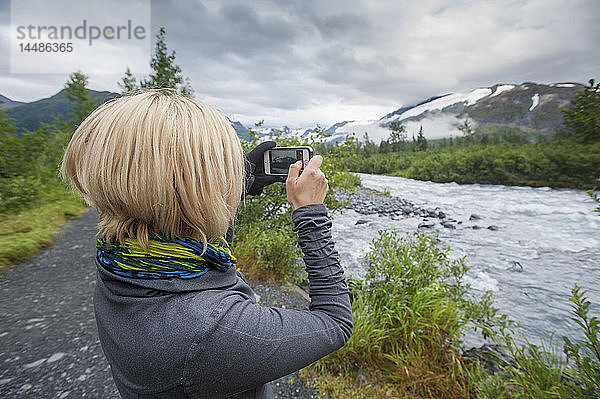 Frau fotografiert mit einem Smartphone den Portage Creek  Portage Valley  Southcentral Alaska