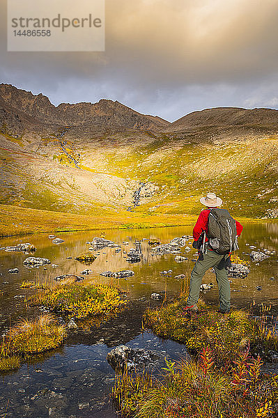 Ein Wanderer hält an einem Herbsttag in Süd-Zentral-Alaska an  um sich den Lower Hidden Lake im Chugach State Park anzusehen.