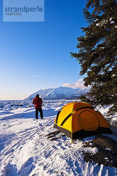 Ein Mann auf seinem Winterlagerplatz am Bird Point mit dem Turnagain Arm im Hintergrund  Southcentral Alaska