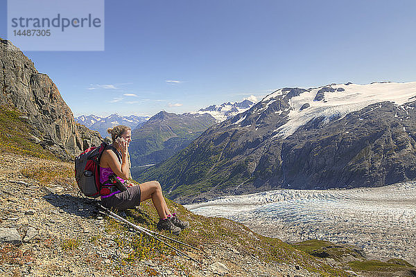 Wanderin macht eine Pause und telefoniert neben dem Exit Glacier im Harding Icefield bei Seward  Kenai Fjords National Park  Kenai Peninsula  Southcentral Alaska  Sommer  HDR