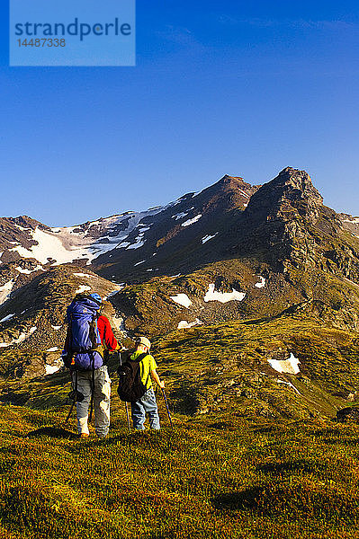 Vater und Sohn auf Rucksacktour in der Nähe des Hatcher Passes in den Talkeetna Mountains mit dem Bald Mountain Ridge im Hintergrund  Süd-Zentral-Alaska  Sommer